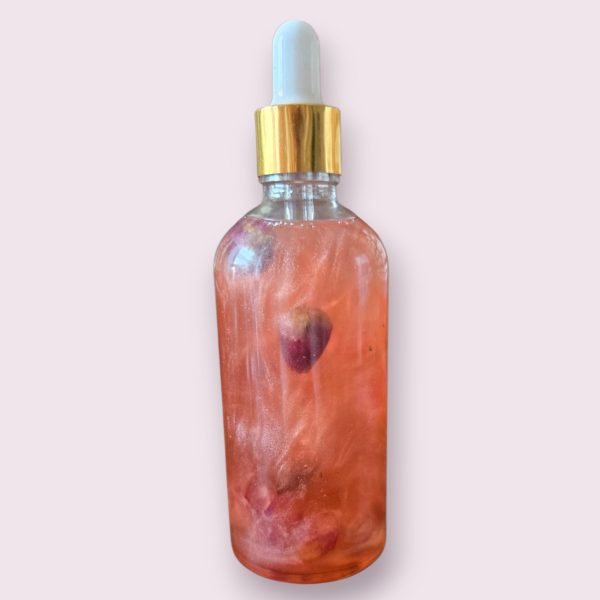 Flacon d’huile de rose pour le corps scintillante, soin naturel hydratant avec un voile lumineux subtil.